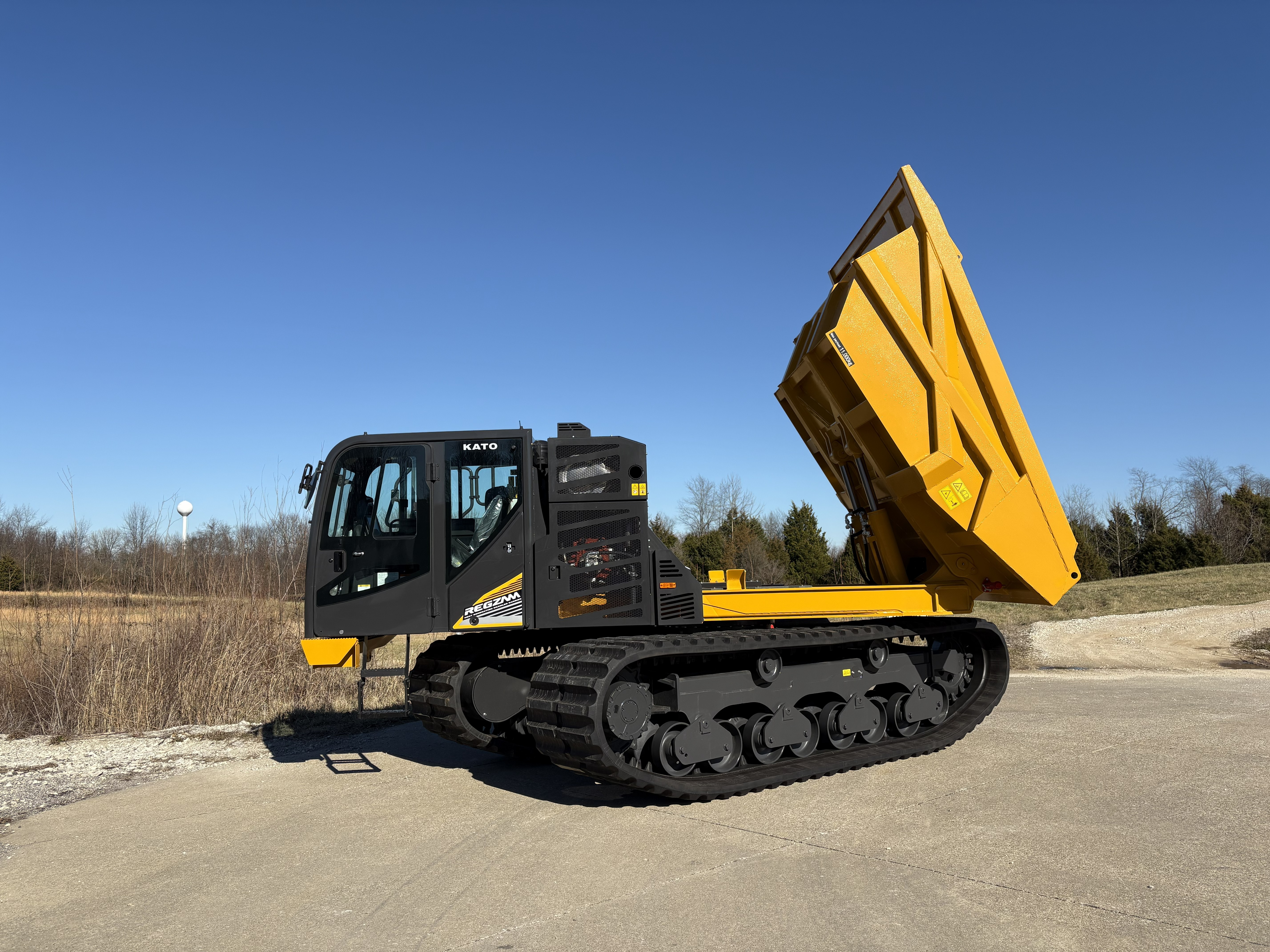 Yellow and black KATO tracked dump truck with raised bed on gravel lot