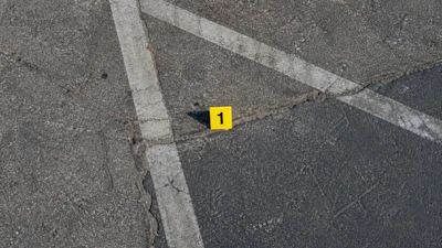 Yellow evidence marker numbered 1 on asphalt with white painted lines