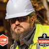 Construction worker wearing white hard hat, dark sunglasses, and neon yellow safety vest with Ergodyne branding