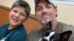 Man and boy smiling with black and white dog indoors