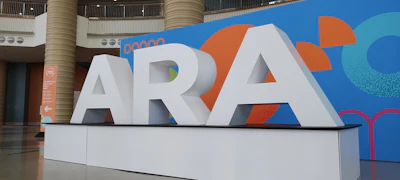 Large white ARA sign with colorful geometric backdrop in modern building plaza