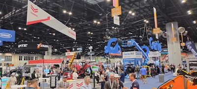 Industrial trade show exhibition floor with heavy equipment, vendor booths, and construction machinery displays