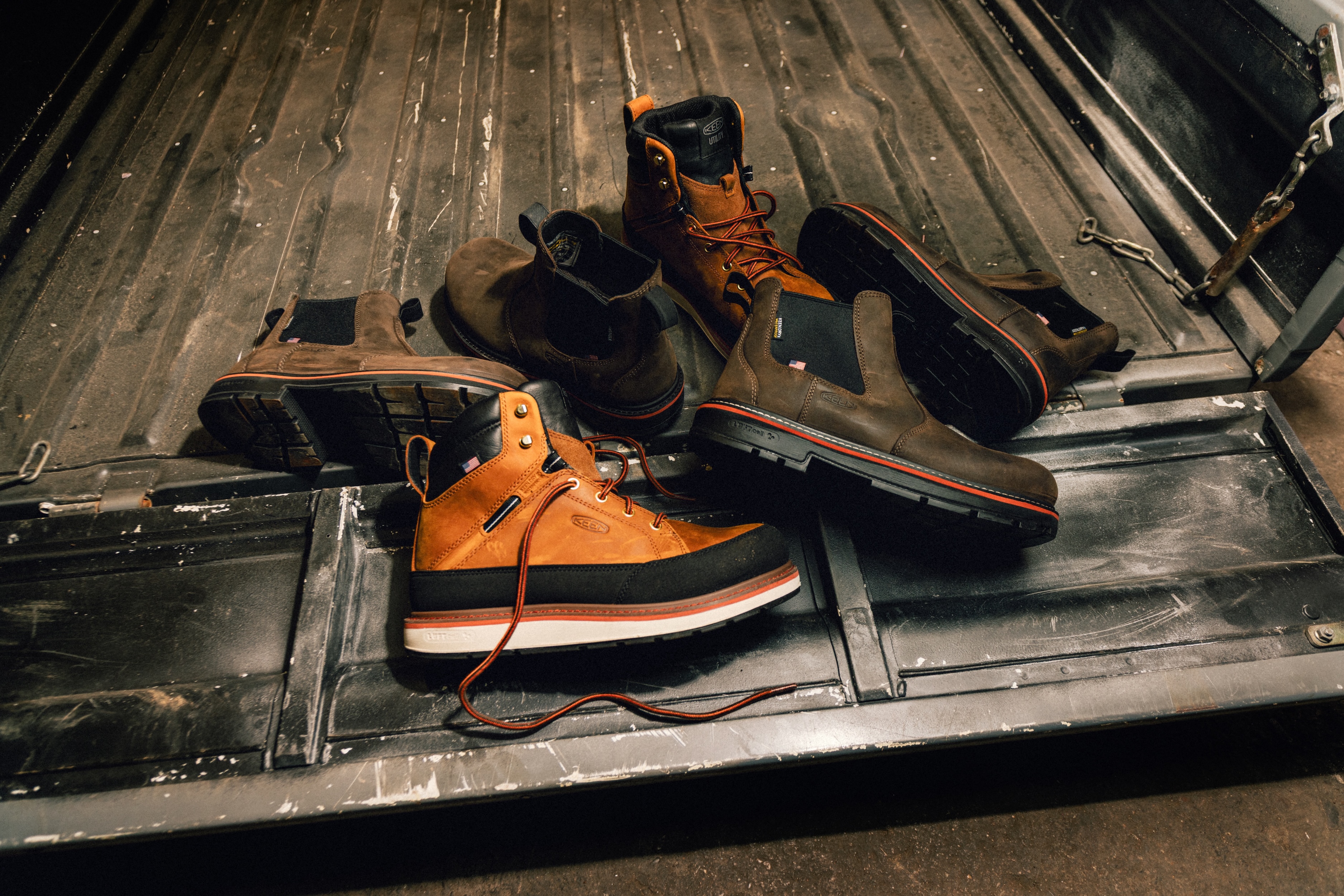 Orange and black work boots with safety gear arranged in a truck bed