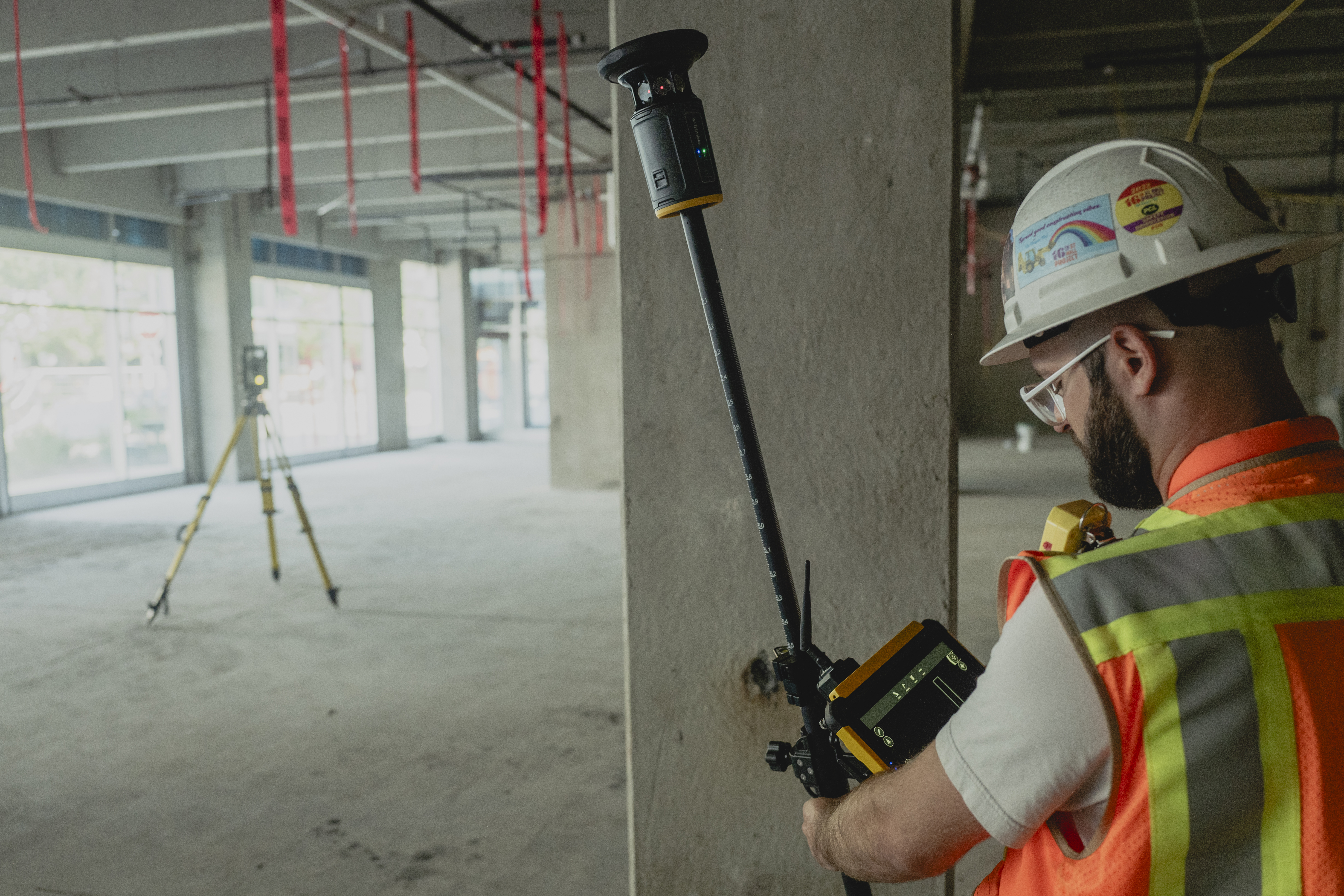 Construction worker using laser level tool on concrete wall at job site