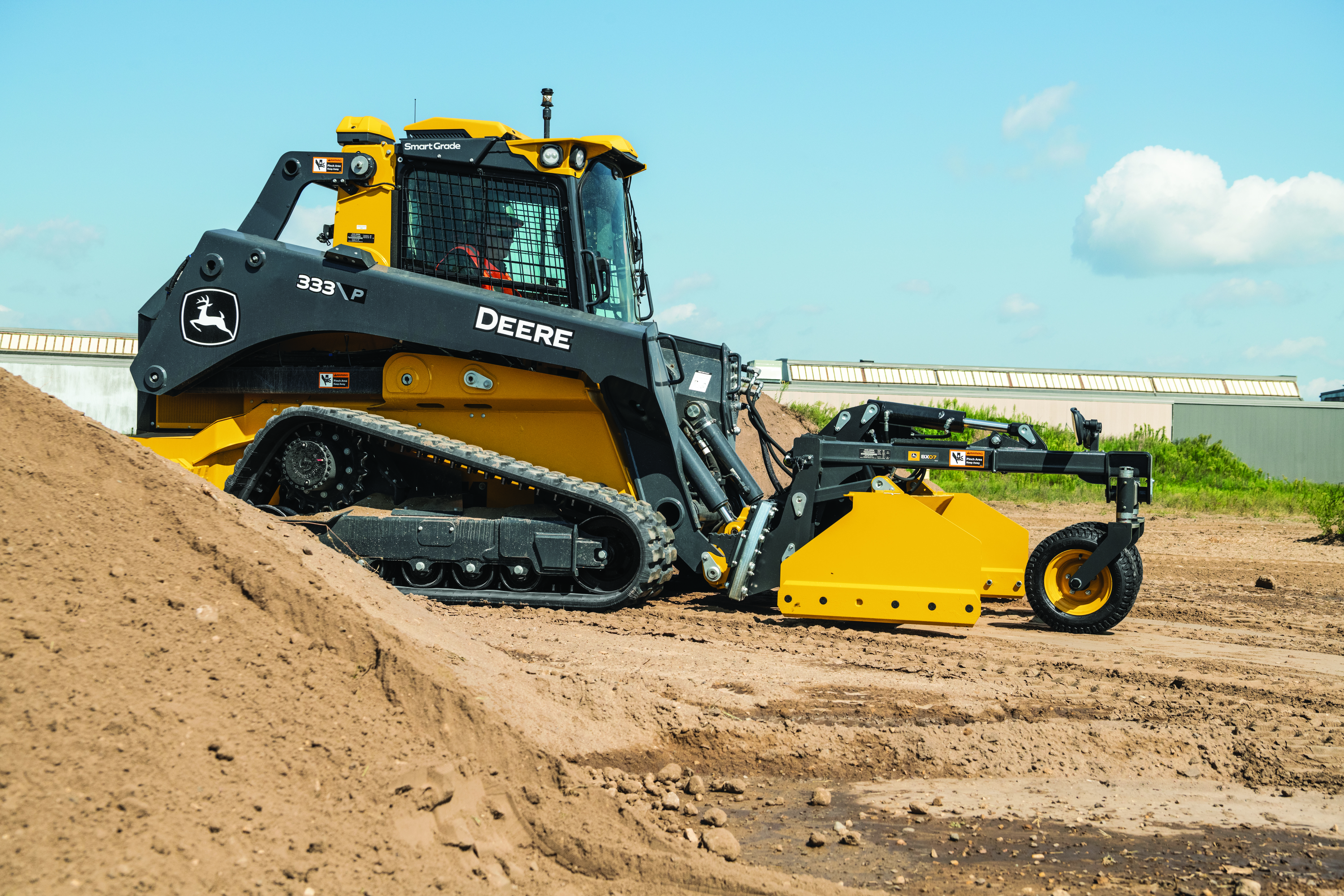 Yellow and black John Deere track loader with blade attachment on dirt site