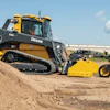 Yellow and black John Deere track loader with blade attachment on dirt site